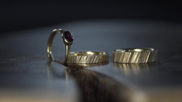 Goldene Eheringe mit Verlobungsring  im bewegenden Scheinwerferlicht