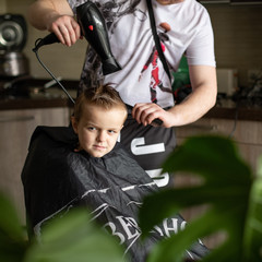 Barbershop and hairdressing at home. Men's and children's haircuts. The hairdresser cuts the boy. Stylish hairstyle for a child