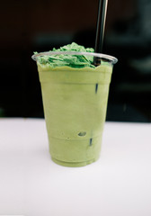 Blurry image Matcha, a cup of green tea blended on the table in  coffee shop at market.