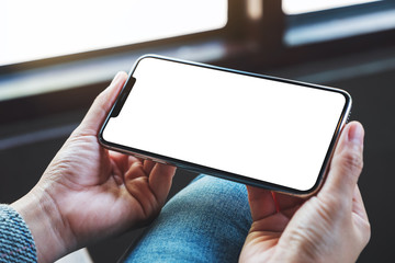 Mockup image of a woman holding mobile phone with blank white desktop screen