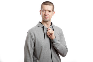 A sports confident athlete is a man who zips a hooded jacket lock. A look into the camera. Isolated