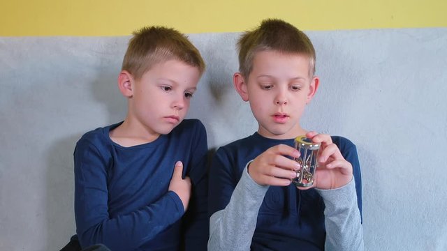 A Metal Brain Teaser In The Hands Of A Child. The Boys Are Trying To Solve Easy Puzzle, Get An Object Out Of The Cage. 