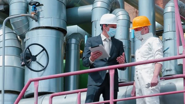 Communication of two masked workers in the technical part of the factory. Statement of work task for staff. Stress manager in the workplace. Coronavirus COVID-19