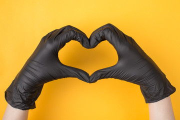 Top above overhead view photo of woman's hands in black gloves making heart isolated on yellow...