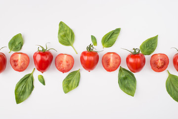 Top above overhead view photo of a row of tomatoes and spinach isolated on white background
