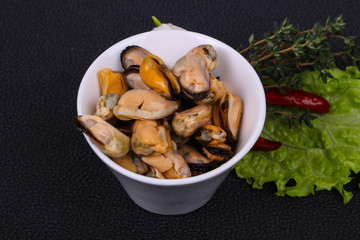 Pickled mussels in the bowl served pepper, garlic and salad