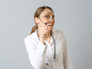 Portrait of beautiful female doctor looking through loupe