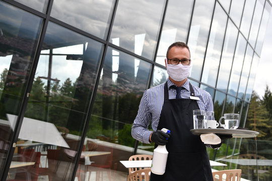 Waiter cleaning the table with Disinfectant Spray in a restaurant