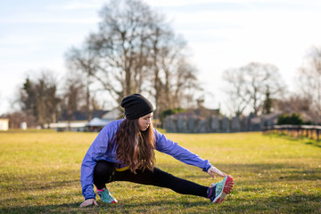 A young Caucasian woman in sportswear is engaged in warm-up and fitness in the Park. Concept of sport, health and active life