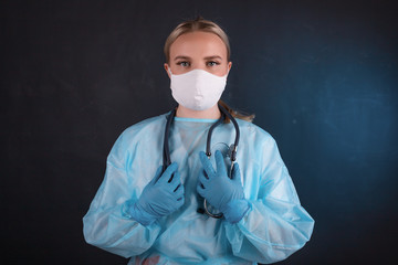 Portrait of a doctor in a mask and medical gown on a black background.