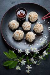 Steamed panasian pork and beef dumplings served on a black plate, vertical shot, elevated view, selective focus