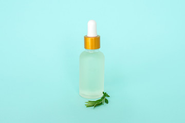 Glass cosmetik bottle with oil. container for a product for women with small white flowers on a turquoise background. Cosmetic jar. Place for text. Dropper glass Bottle Mock-Up