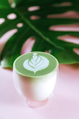 Hot green matcha latte with green leave on colorfull background
