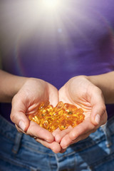 Fototapeta premium A handful of vitamin d capsules are in women's hands. Blurred background