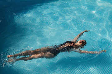 fashion photo of a sexy beautiful girl in elegant bikini posing and takes a sunbath in the swimming pool