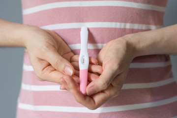 Woman holding pregnancy test, New life and new family concept.Pregnancy test in female hand on blurred background