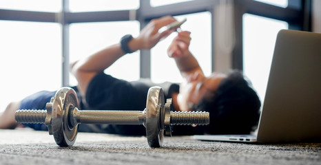 Naklejka premium close up dumbbell with young man in sit-up pattern on the floor to workout with online trainer course from website for quarantine lifestyle and healthy concept