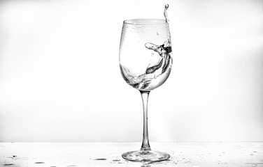 Water in a wine glass. Splash of liquid on a white background. Isolated object. Spray. Selective focus.