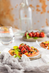 gourmet pizza with tomatoes, olives and basil leaves on wooden table