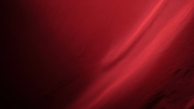 The chic and elegant texture of the moving folds of light red fabric on a black background under dramatic lighting. Slow Motion 200 FPS

