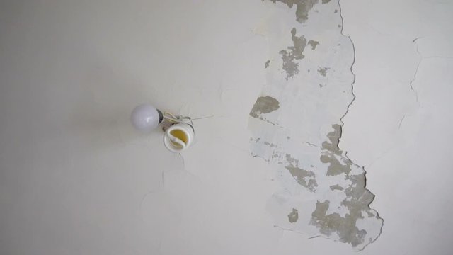 White ceiling. The plaster fell off. Cracks in the ceiling. Bad repair. The result of the flood. Repair in the room. The mistake of the builders.