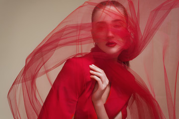 Fashionable portrait of a girl model with waving red veil