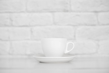 Fototapeta na wymiar white mug on a white table against a white brick wall