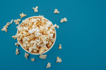 Obraz na płótnie Canvas Popcorn in a bowl on blue background, top view.