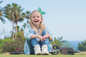 Active little girl with scooter  in park outdoors on summer day.  Summer time fun