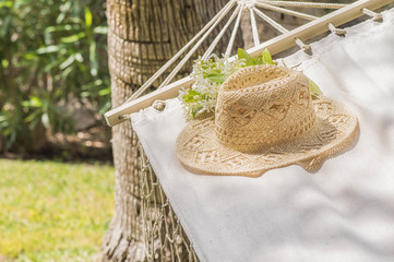 Straw hat on a hammock in a sunny summer day. Rest in the garden. Summer time fun