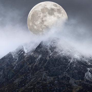Epic digital composite image of Supermoon above mountain range giving very surreal fantasy look to the dramatic landscape image