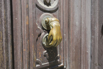 Obraz premium door knocker, copper hand with ornaments on a brown wooden door