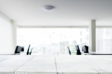 Empty wooden desk space over blurred office or meeting room background. Product display.