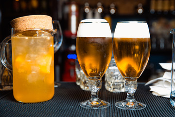Decanter with orange juice and glasses of beer is standing at the bar counter.