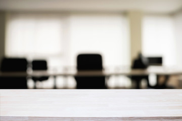 Empty wooden desk space over blurred office or meeting room background. Product display.