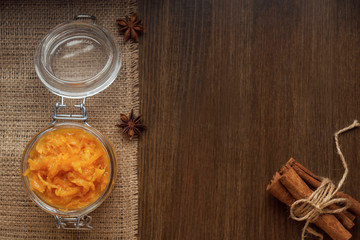 Obraz na płótnie Canvas Jar of orange jam on burlap and cinnamon sticks with star anise
