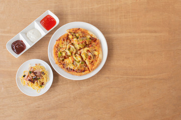 Pizza with spaghetti, tomato sauce, chilli sauce, mayonnaise sauce on wooden table