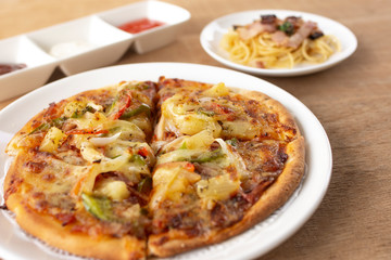 Pizza with spaghetti, tomato sauce, chilli sauce, mayonnaise sauce on wooden table
