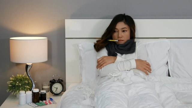 sick woman feeling cold and using thermometer to checking her temperature in a bed, 4k Video