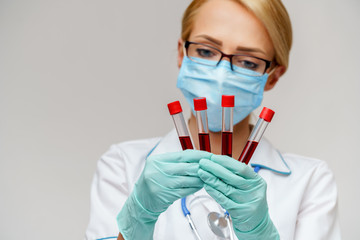 medical doctor nurse woman wearing protective mask and gloves - holding virus blood test tube