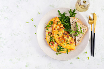 Omelette with tomatoes, ham, cheese and green herbs on plate.  Frittata - italian omelet. Top view, overhead, copy space