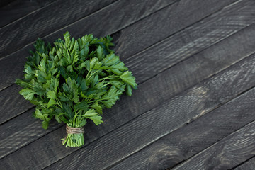 A bunch of green parsley lies on a wooden background.