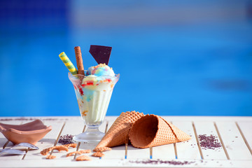 Panorama of glass with rainbow ice cream and colorful syrup on blur bokeh background with copy...