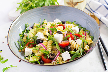 Pasta salad with tomato, avocado, black olives, red onions and cheese feta. Mediterranean cuisine.