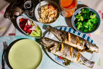 Baked fish Laurak in the oven is on the table with snacks.