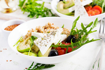Breakfast oatmeal porridge with greek salad of tomatoes, avocado, black olives and arugula. Healthy balanced food.