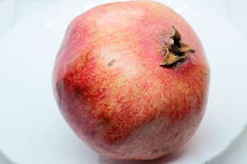 Ripe beautiful red pomegranate is located on white