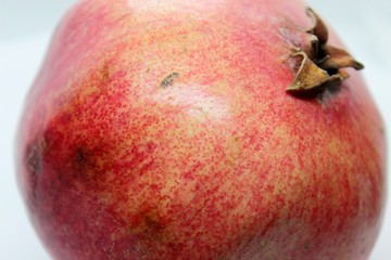 Ripe beautiful red pomegranate is located on white