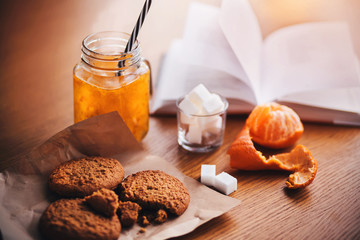 On the wooden table is breakfast - a mug with sea buckthorn Morse, peeled tangerine, oatmeal sweet...