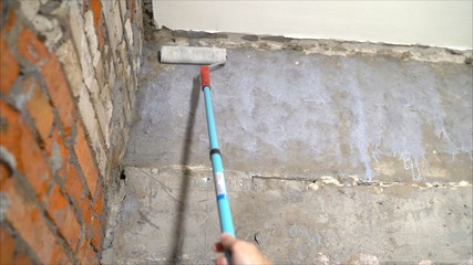 Primed walls with a roller. Background of wet concrete wall. The concept of apartment renovation, construction and finishing works, the